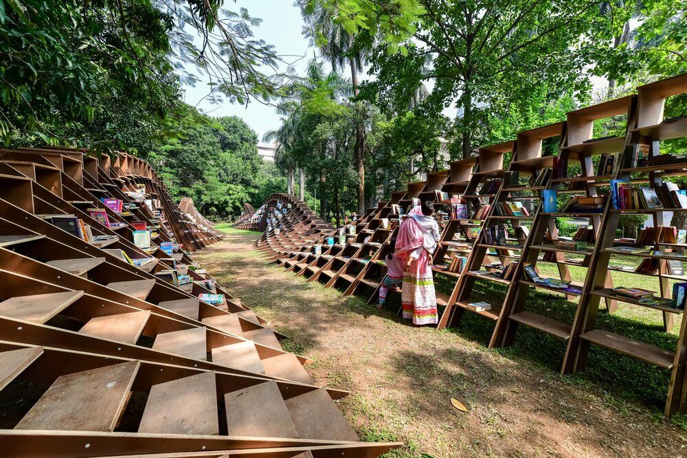 Image of stacked books and lady with a kid at the BookWorm Pavilion designed using Rhino 3D by NUDES Design Studio