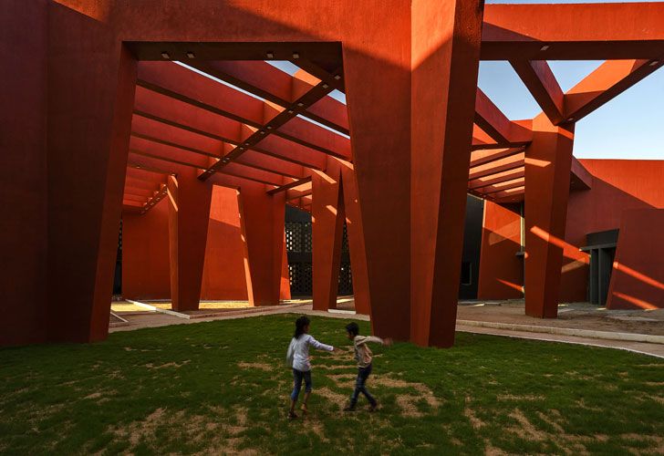 Two children playing in the shaded area in between the tall columns at the Rajasthan School