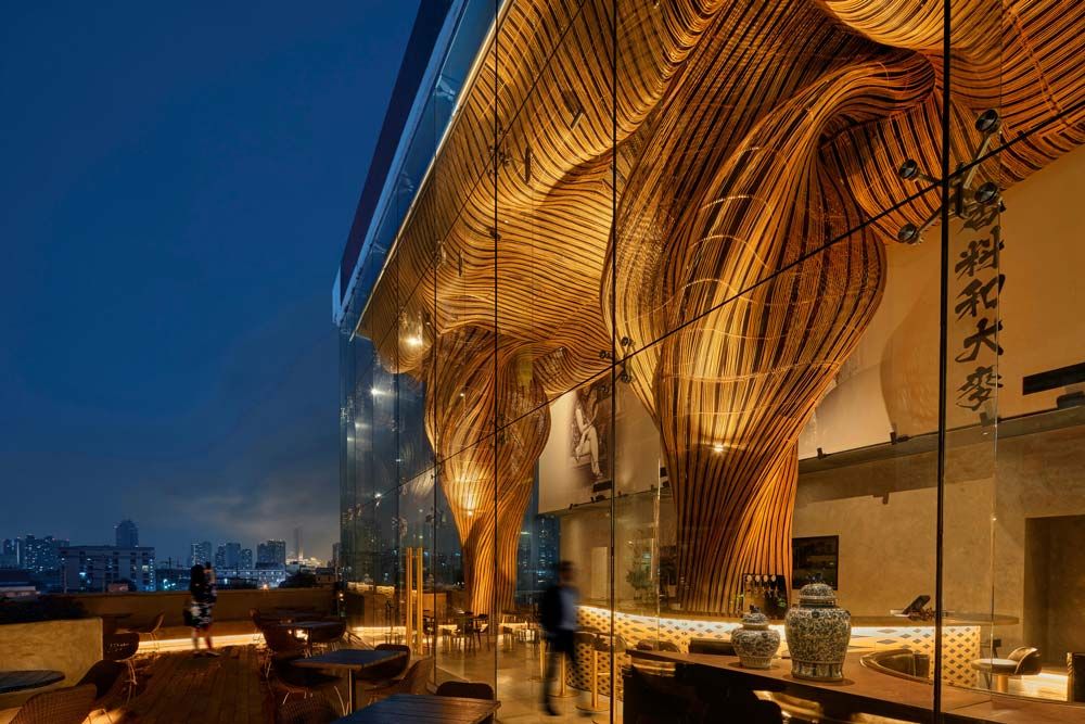 The rattan columns and parametric ceiling seen inside the restaurant at dusk