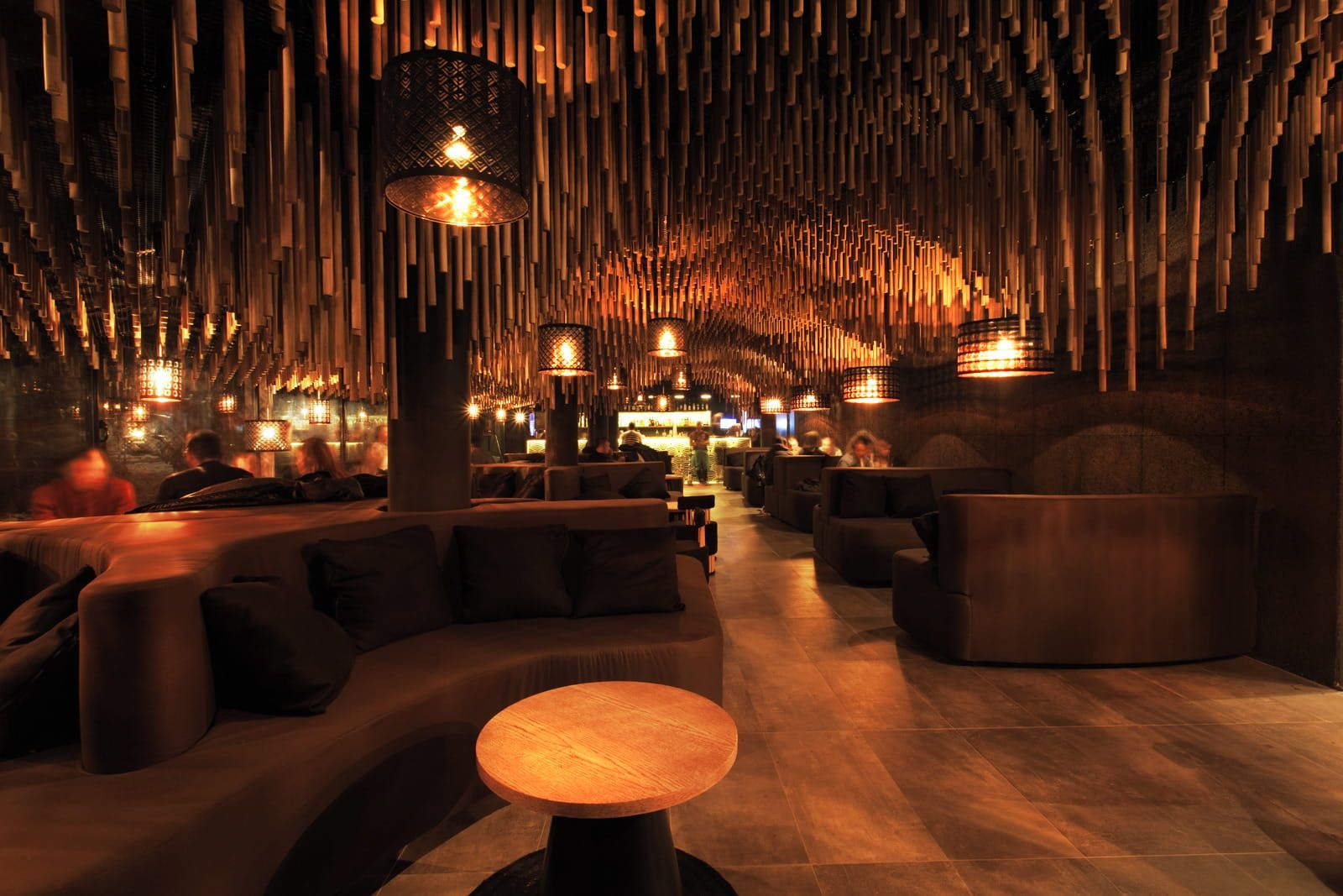 the wood cylinders hanging from the ceiling above the seating area in dim light