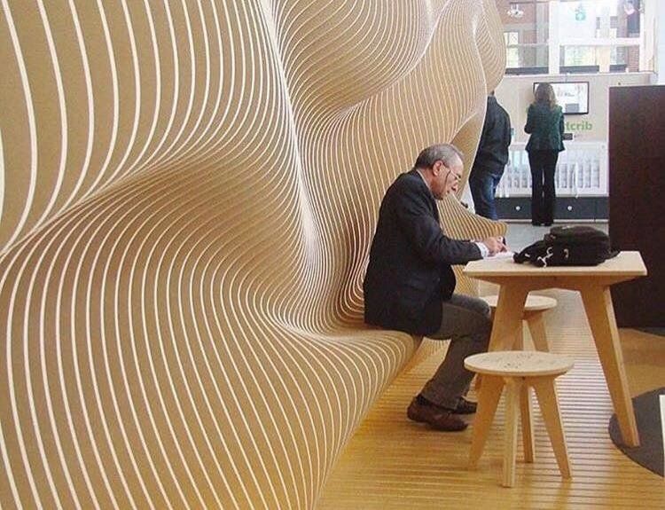 A man sitting on a wavy parametric wall writing notes