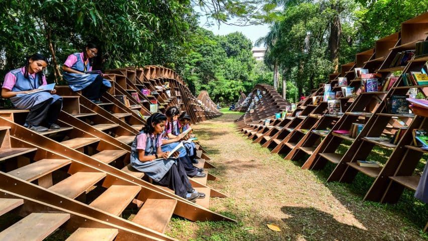 parametric wooden pavilion with bookshelves and seated school children